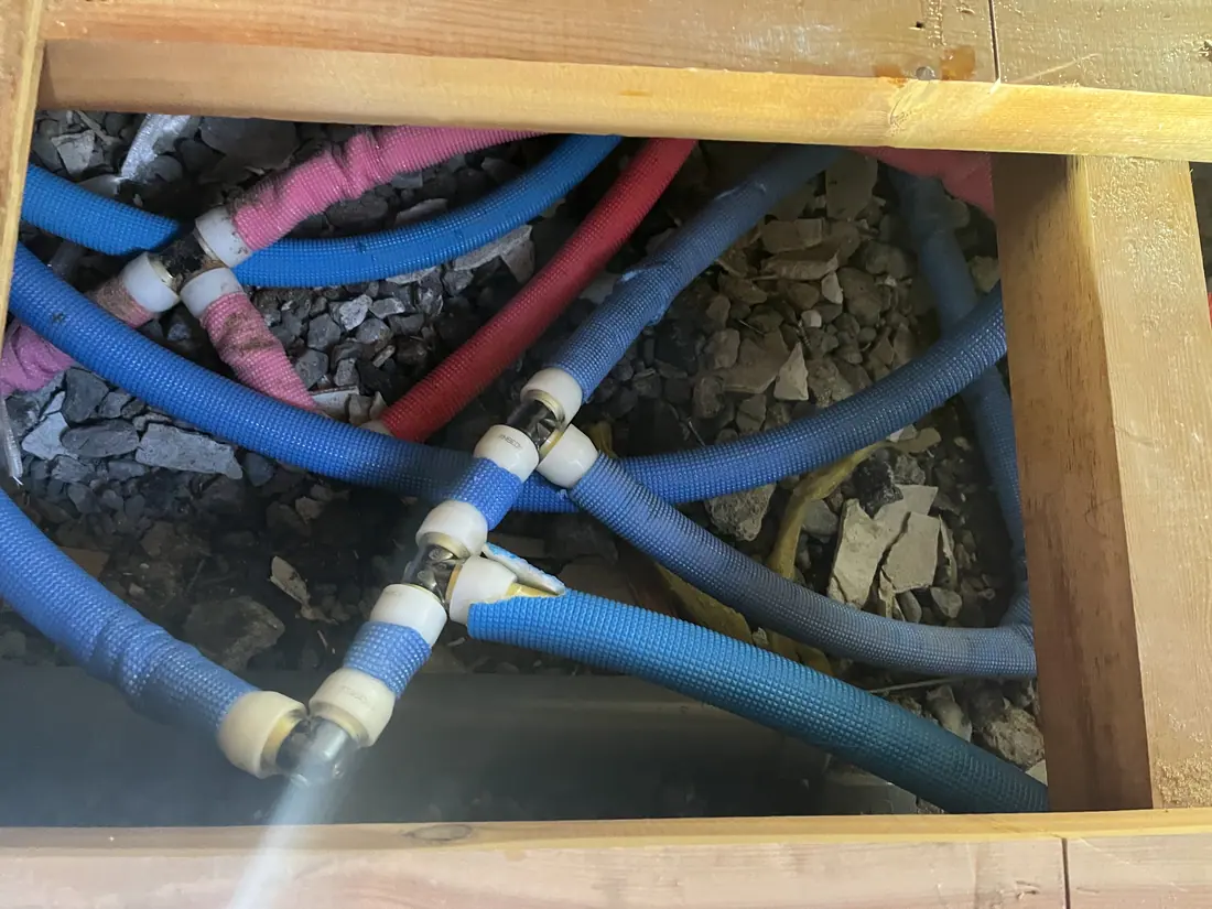 床下に配管された青と赤の給水・給湯管